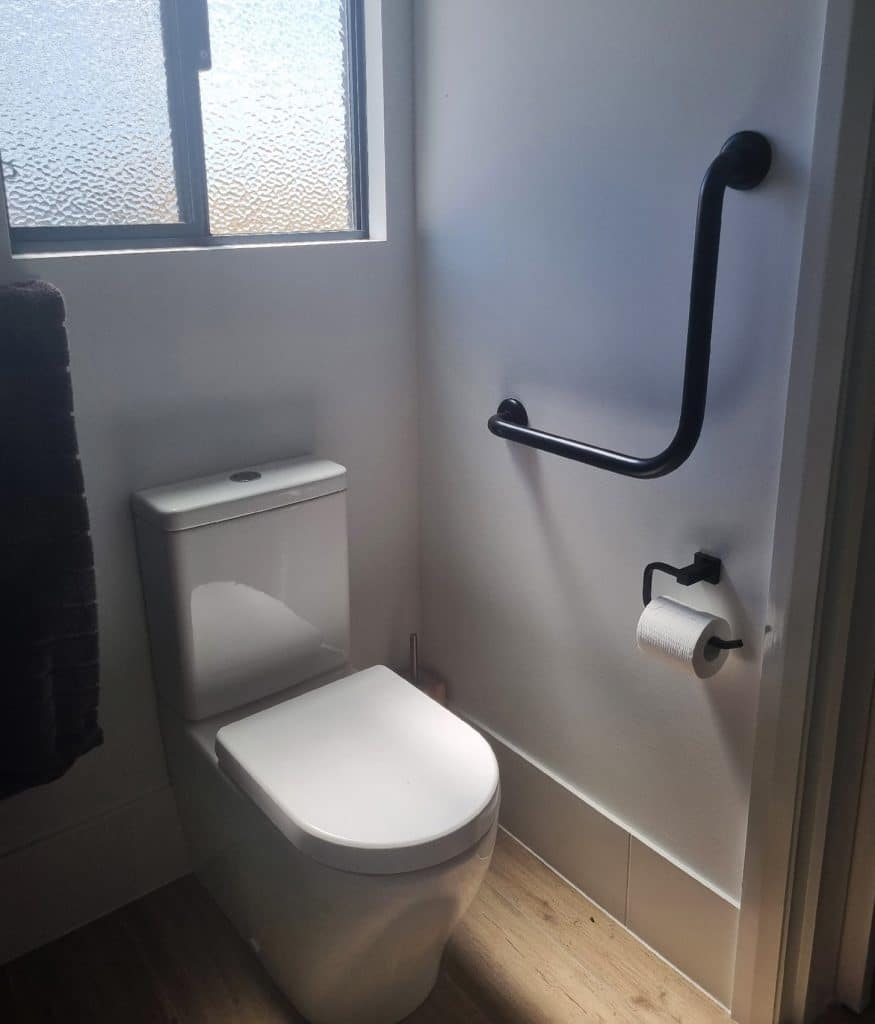 Toilet with a support rail installed into the modular home